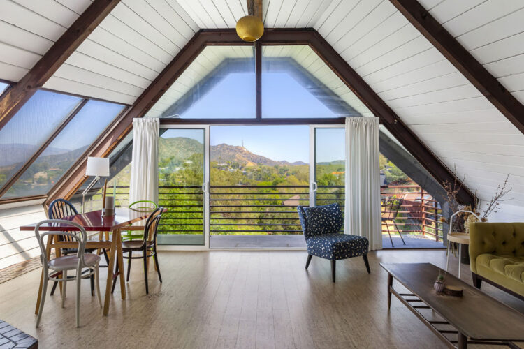 interior of a mid-century boathouse home, white and brown wood with a view of green tree tops