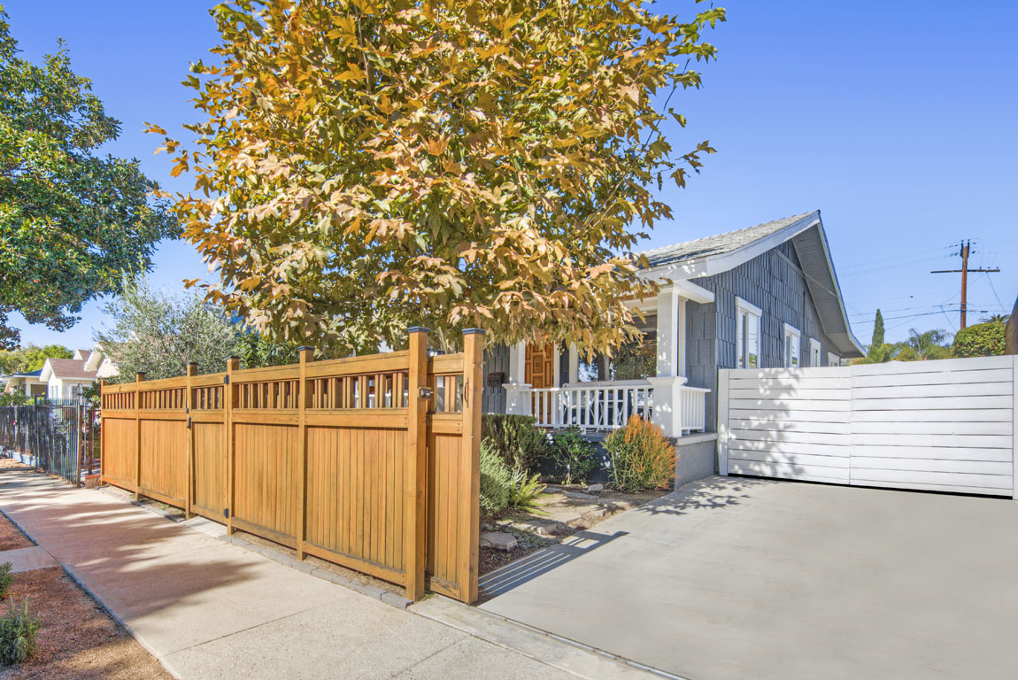 exterior showing a blue cal bungalow with a wooden gate