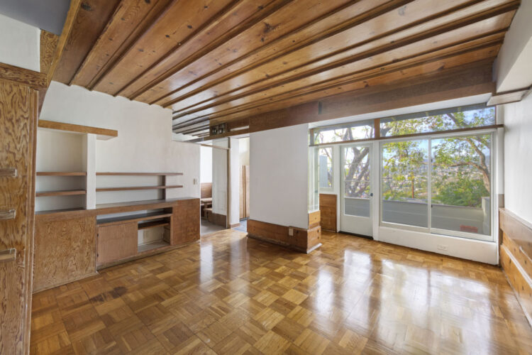interior of a modernist living room with plywood built-ins and wood floors by Schindler