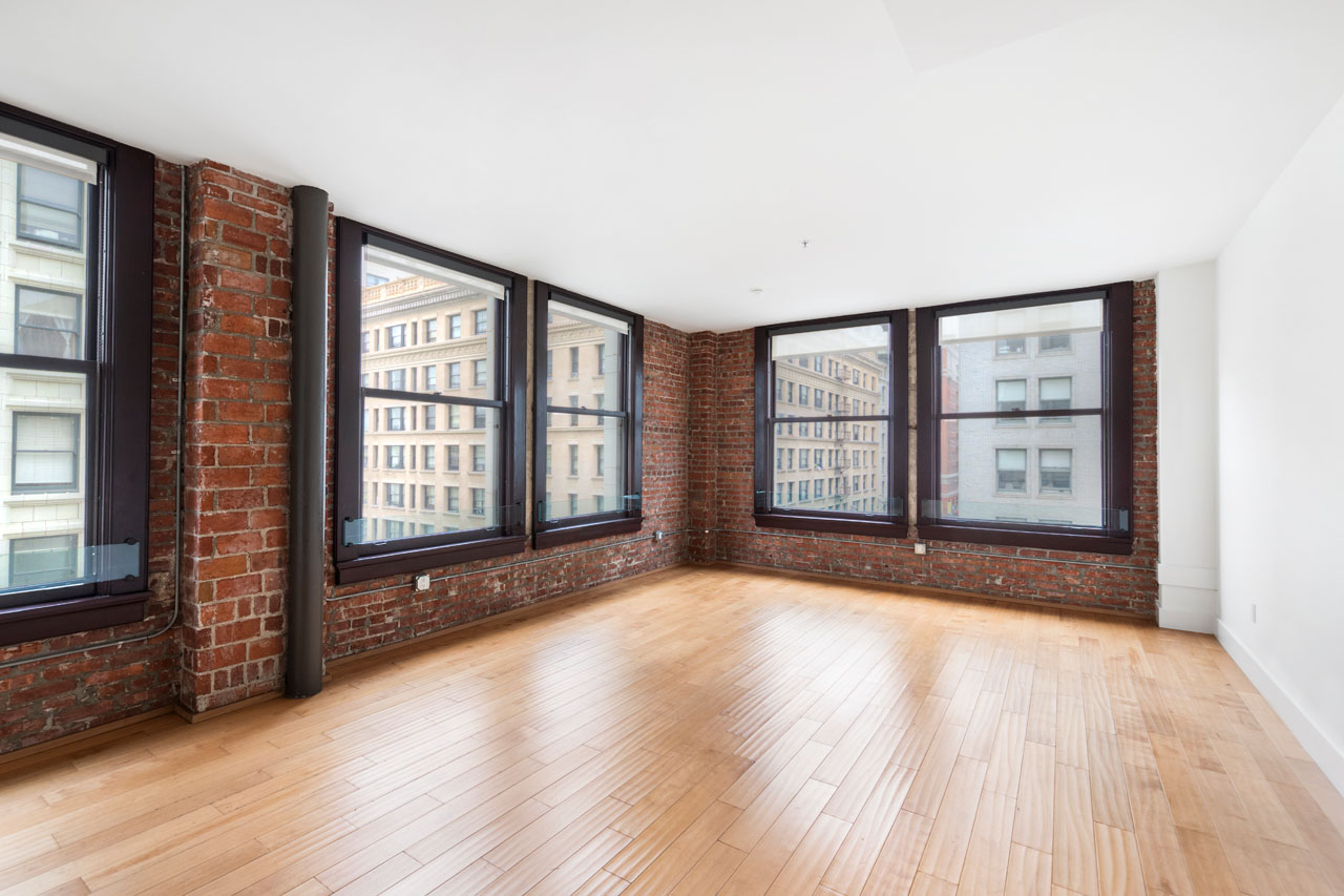 loft interior, wood floors, brick walls and windows showing a view of downtown buildings