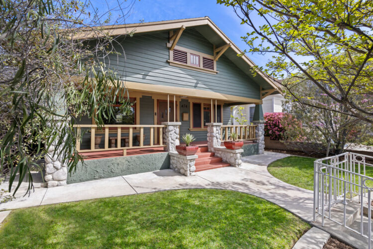 exterior of a green craftsman home with a red deck