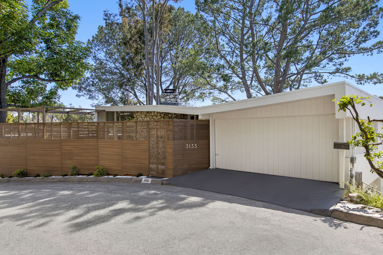 exterior of a midcentury home with a wooden slat fence
