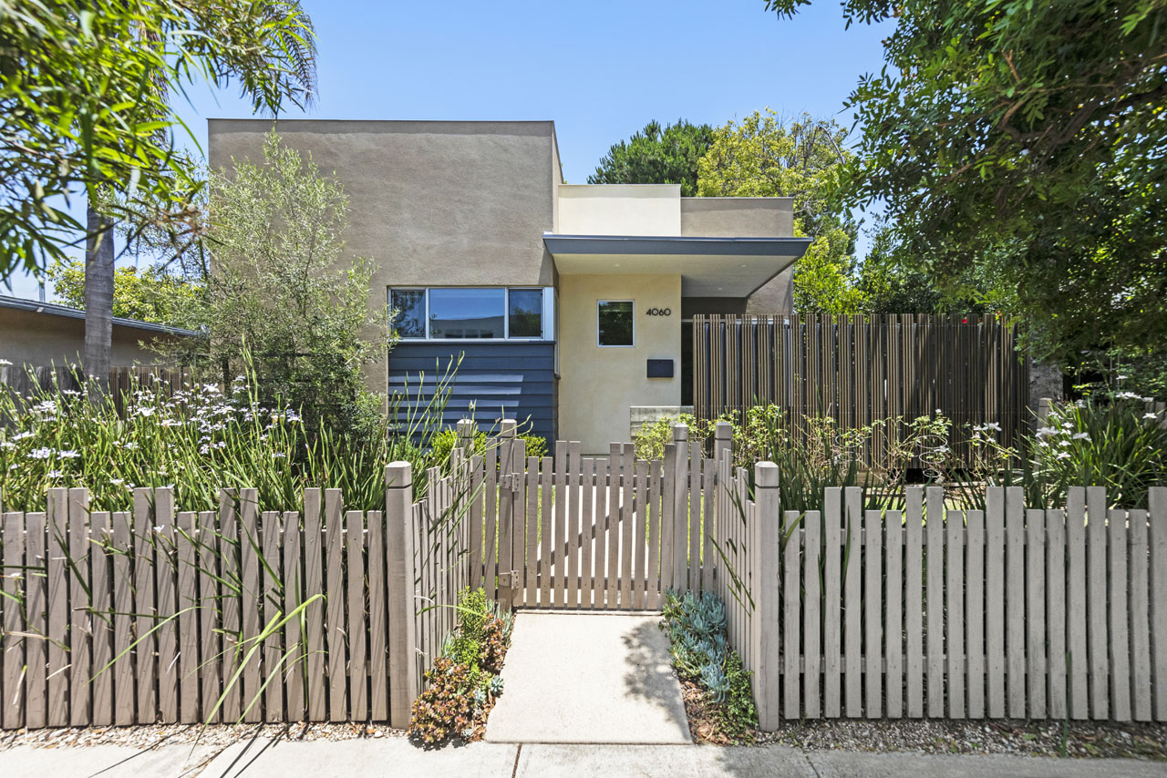 exterior of a contemporary home, grey with green foliage and a wooden slat fence