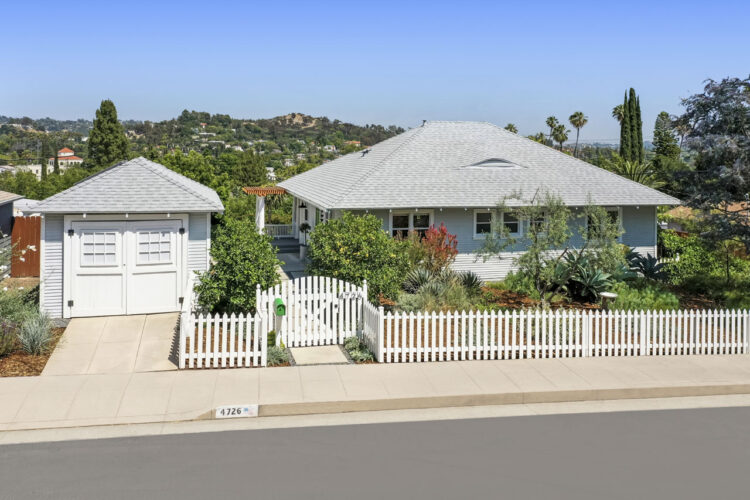 exterior of a light grey traditional home with a white picket fence