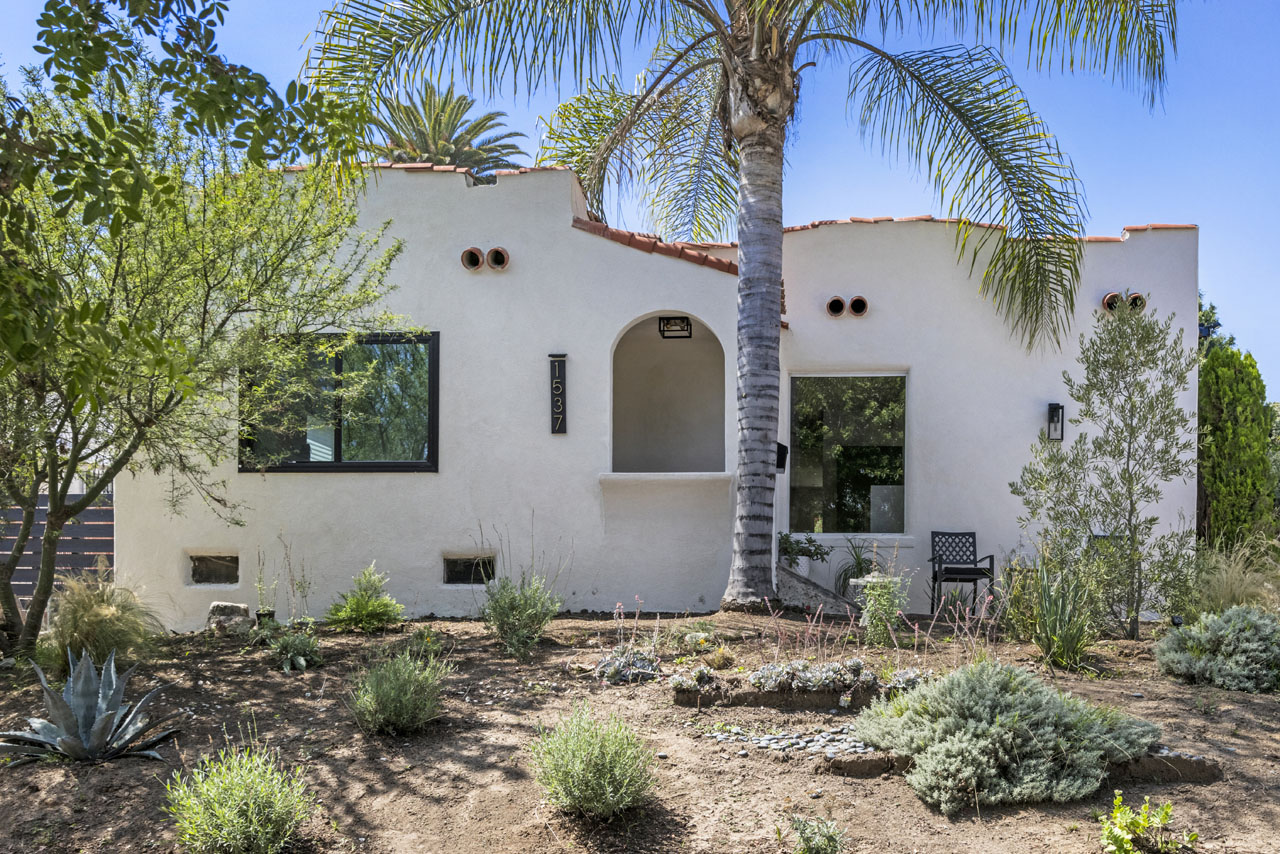 exterior of a white spanish home with a palm tree in the front yard