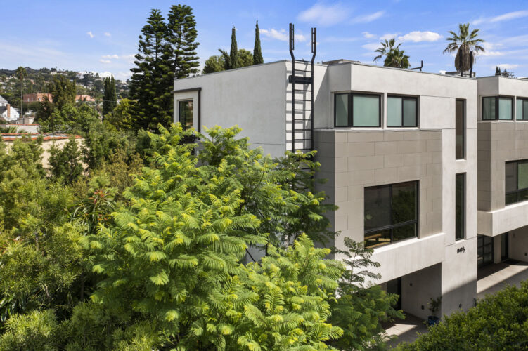 corner exterior of a grey modern home with green foliage