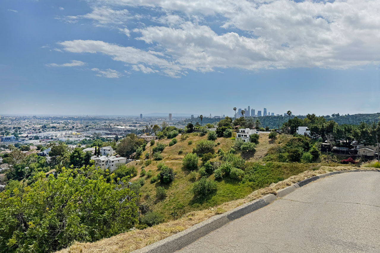 view of a street downslope hillside and a view of downtown los angeles in the distance