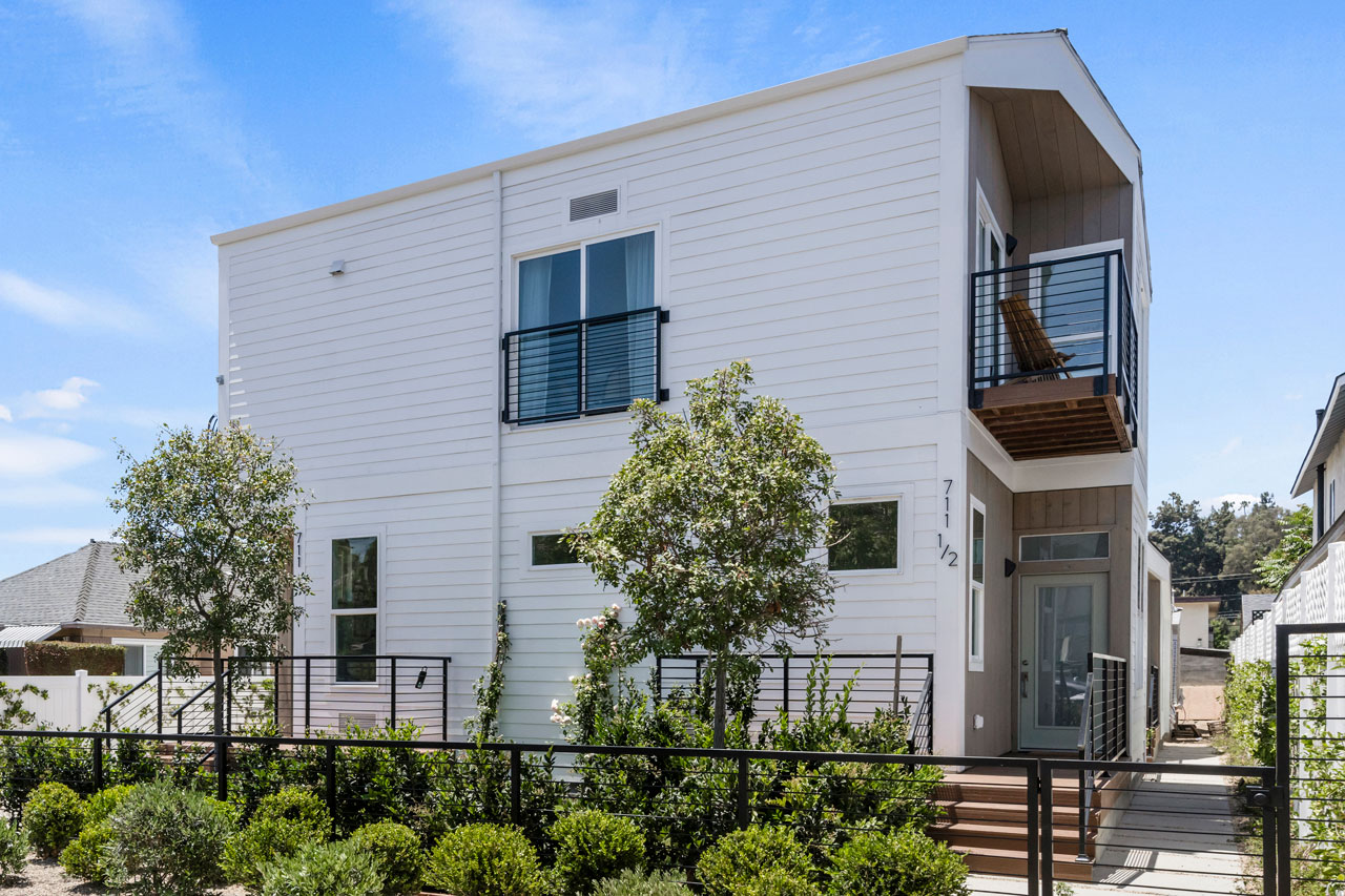 exterior of a two story contemporary tenants-in-common structure with white siding and green landscaping