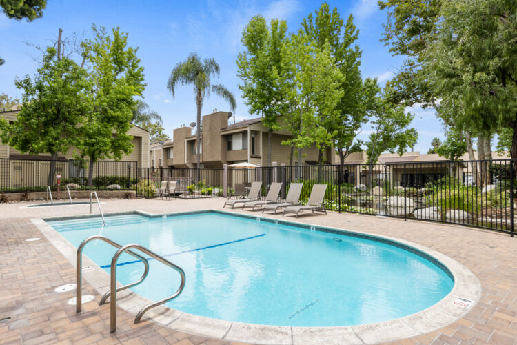 condo community pool with poolside chairs and palm trees