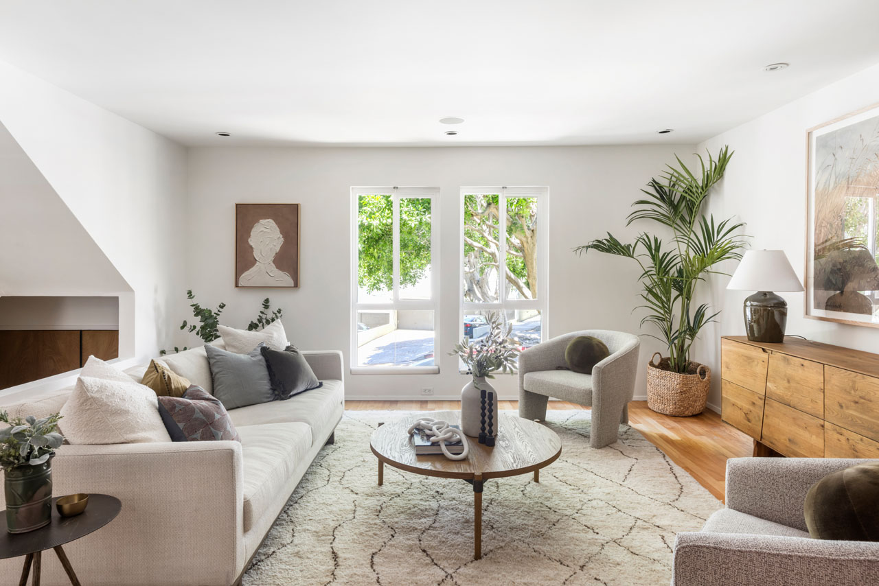 interior of a sunny silver lake condo showing a couch, coffee table, and windows with a view of foliage