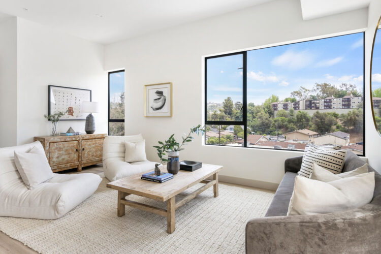 interior of a living room with white furniture and a background scene of neighboring hills