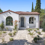 exterior of a single story spanish home painted white with a terracotta tiled roof and drought tolerant landscaping