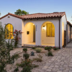 twilight exterior of a single story spanish home painted white with a terracotta tiled roof and drought tolerant landscaping