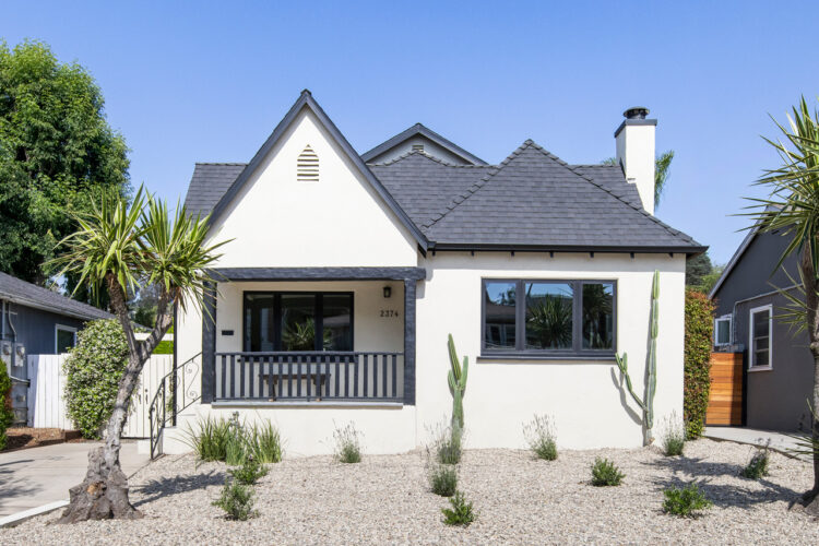 exterior of a white and black traditional home with pointed roof and drought tolerant landscaping