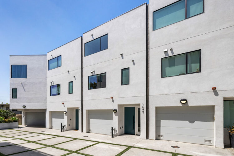 exterior of a contemporary small lot home community, three stories, beige facade, with white garage doors and black trim