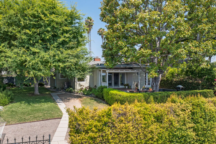 backyard of a traditional style home with a yellow exterior, white garage door and brick fireplace