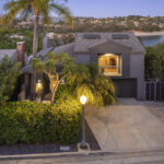 modern home painted grey with a palm tree and blue reservoir in the distance