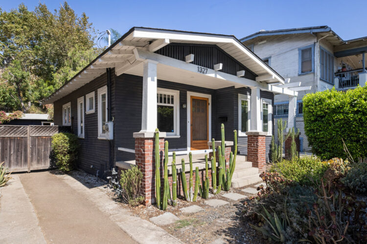single level bungalow home painted blue with white trim and a wooden door and cement porch