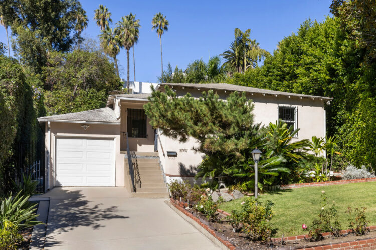exterior of a traditional style home painted beige grey with a cypress tree and green yard
