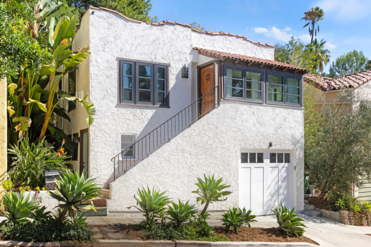 exterior of a two story spanish style home, whitr stucco with tile roof and white garage door