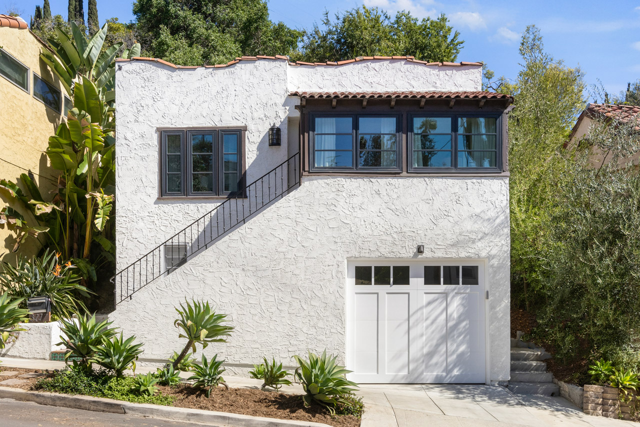exterior of a two story spanish style home, whitr stucco with tile roof and white garage door