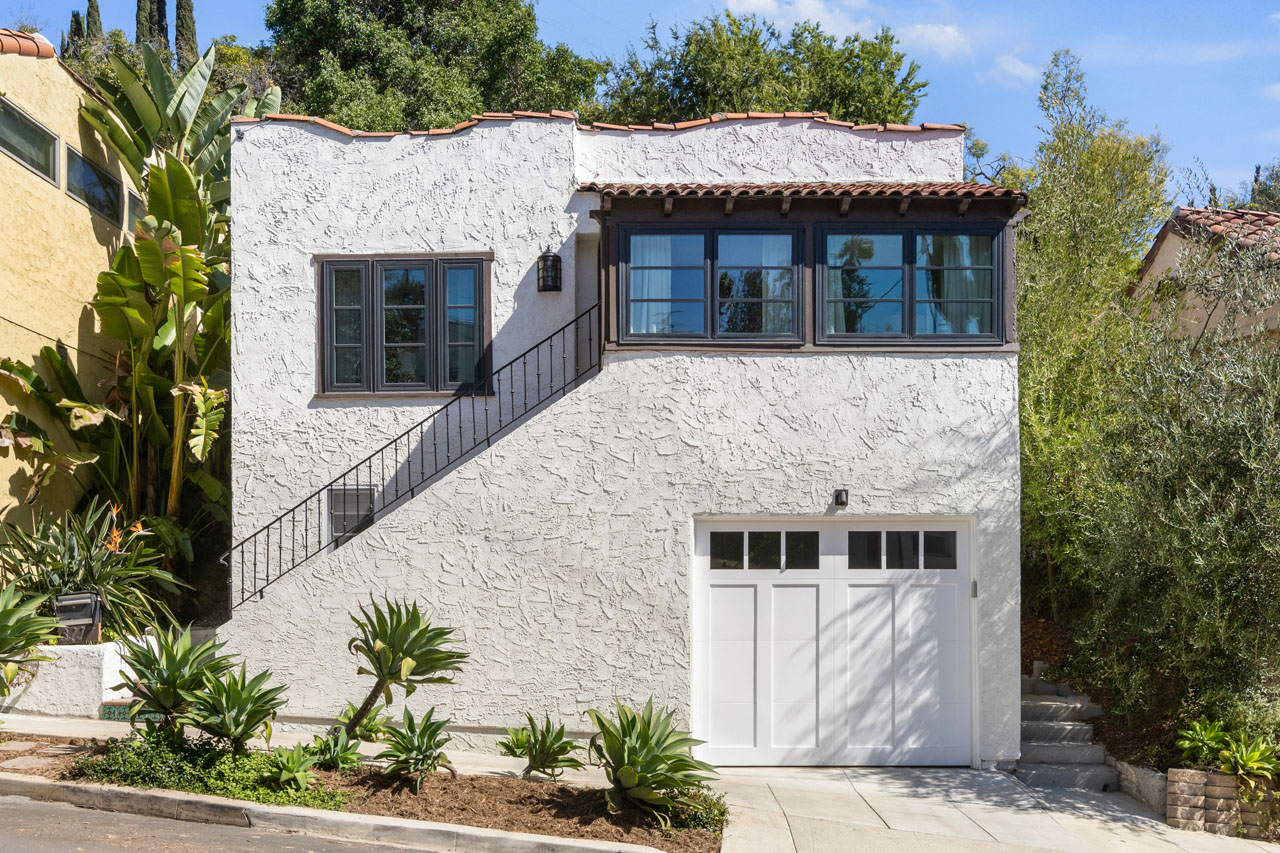 exterior of a two story spanish style home, whitr stucco with tile roof and white garage door