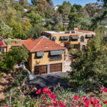 drone view of an expansive mediterranean moorish estate painted yellow with red saltillo tile roof