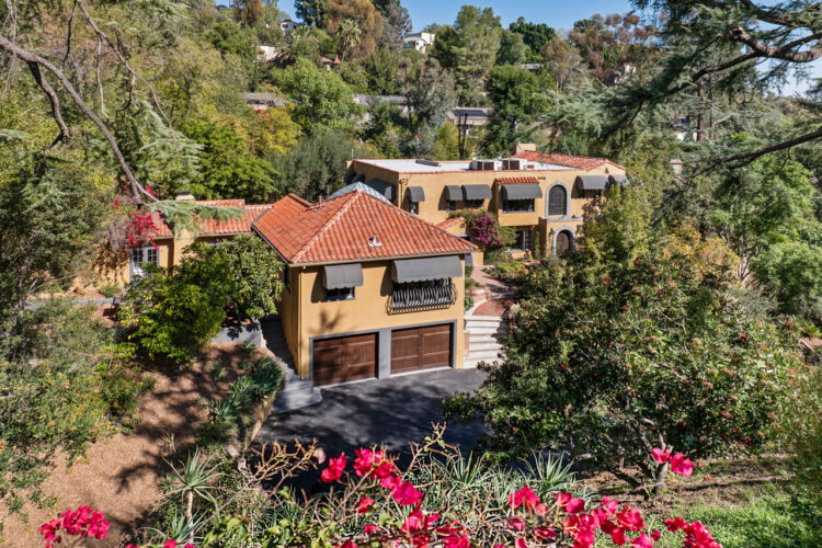 drone view of an expansive mediterranean moorish estate painted yellow with red saltillo tile roof