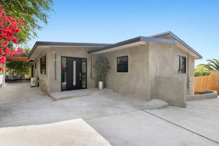 exterior of a grey stucco home with black doors and window details