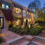 exterior of a mediterranean moorish estate painted yellow with a formal garden and red brick
