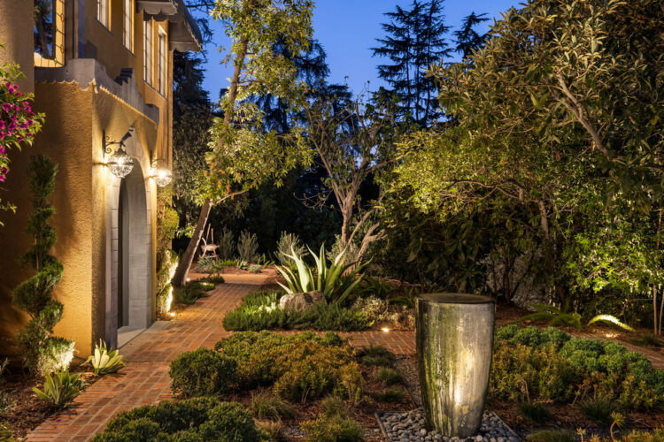 exterior of a mediterranean moorish estate painted yellow with a formal garden and red brick