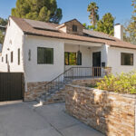 exterior of a traditional home painted white with a stone wall