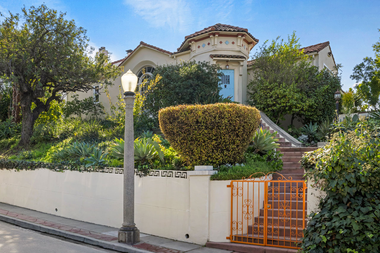 Exterior of a spanish style home with a retaining wall and blue front door
