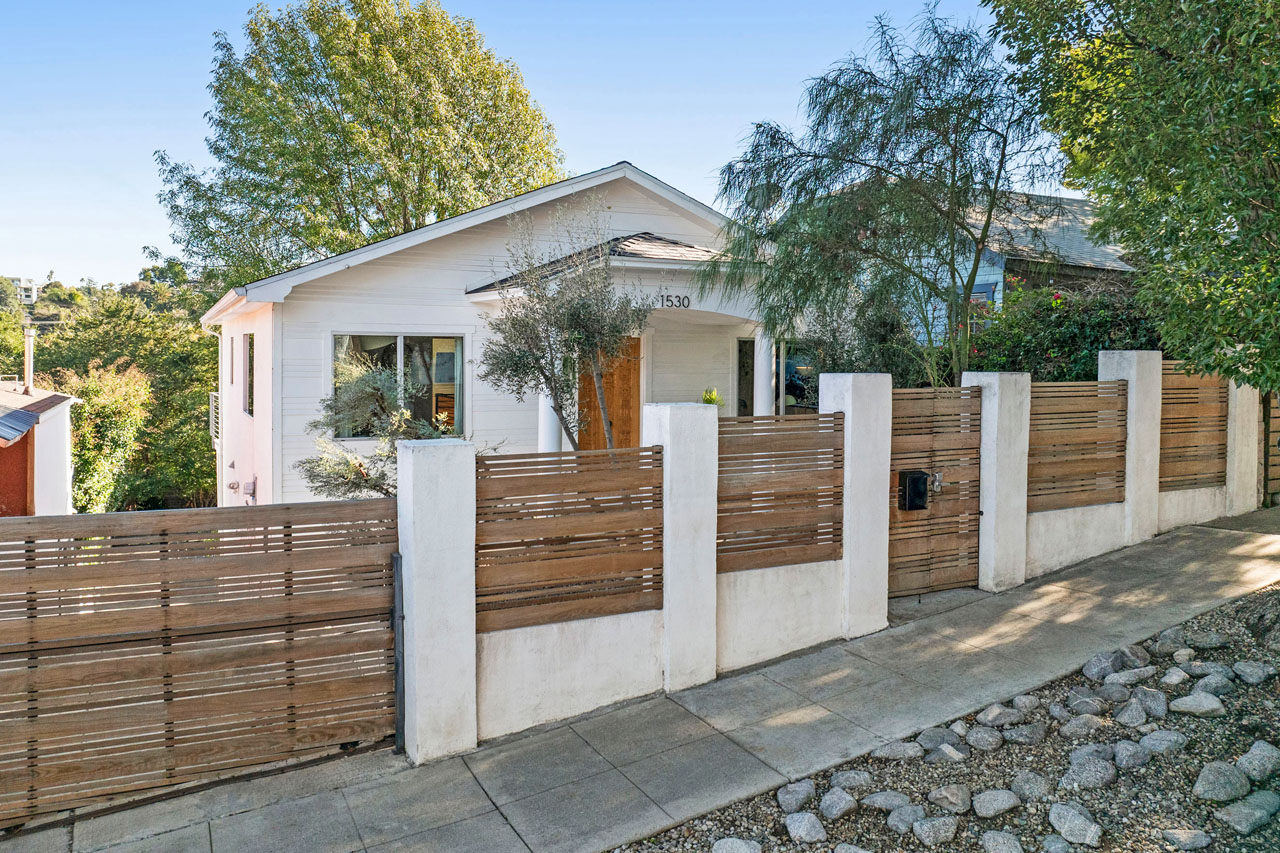 exterior of a traditional home white with wood details and green trees