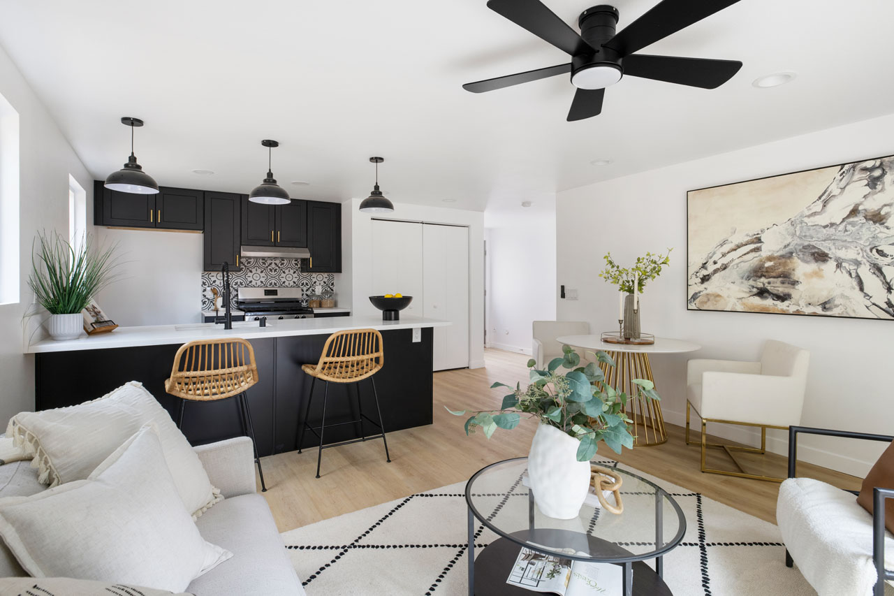 contemporary living room and kitchen with counter, white couch and black fan and light fixtures