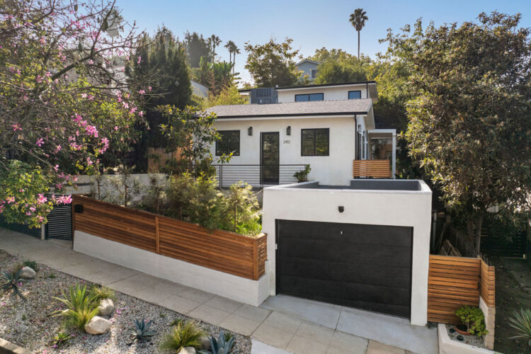 exterior of a contemporary home painted white with black trim and green landscaping around