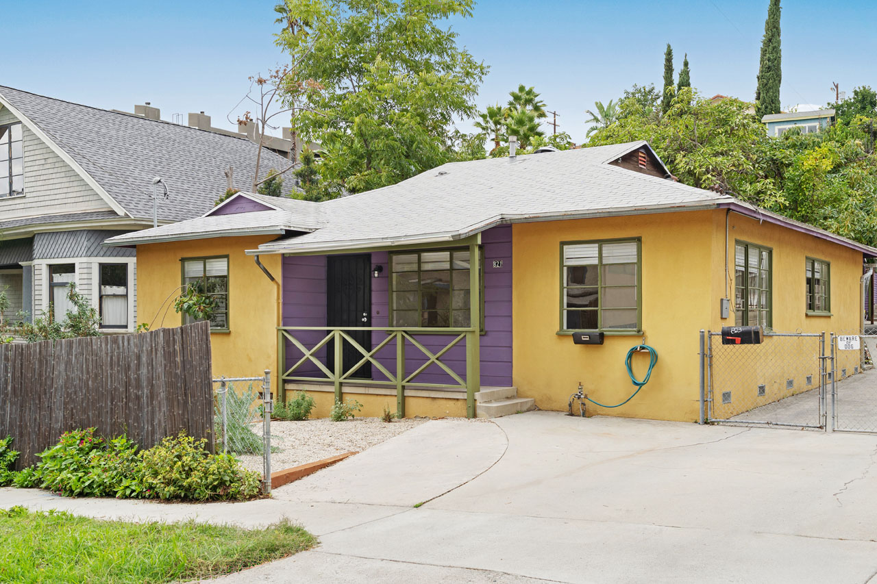 exterior of a bungalow home painted yellow and purple wiht green accents