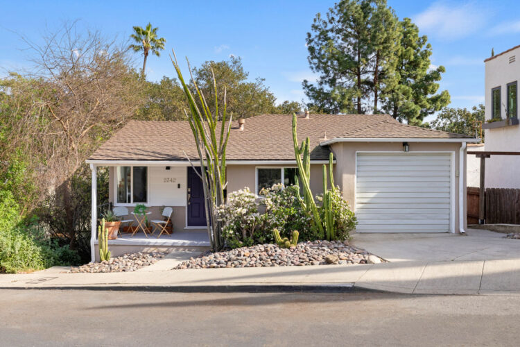 exterior of a western traditional style home painted yellow with white trim and a drought tolerant yard with stones and cactii