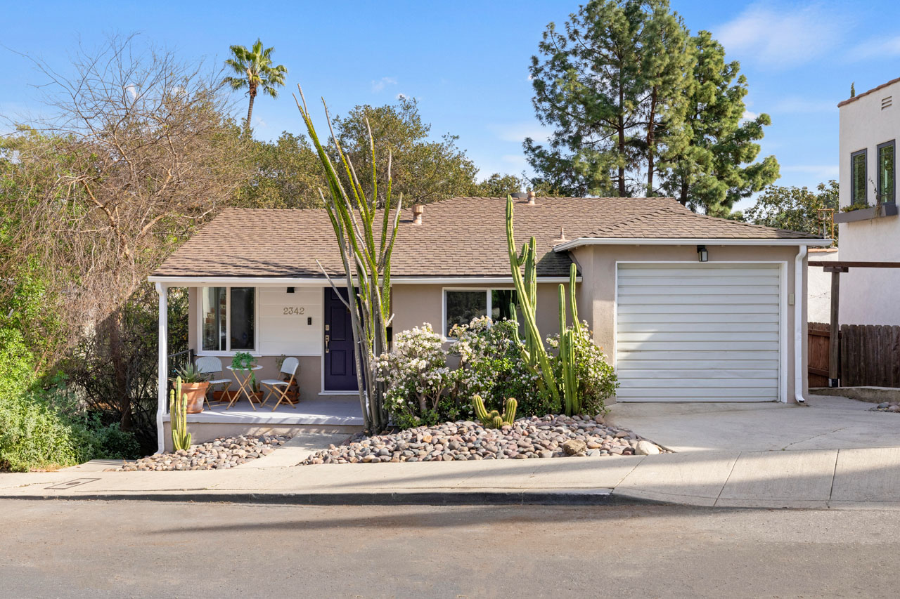 exterior of a western traditional style home painted yellow with white trim and a drought tolerant yard with stones and cactii