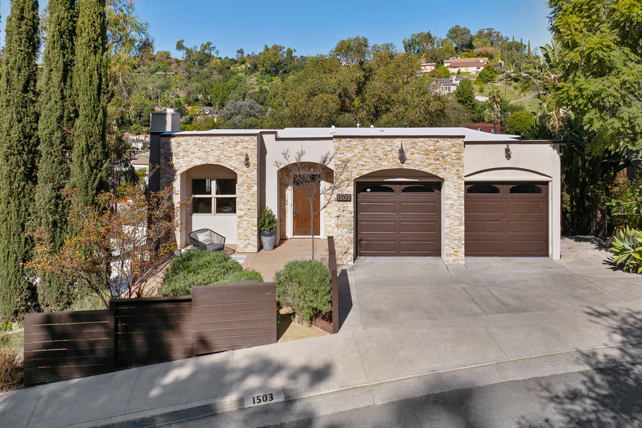 exterior of a hillside home with stone exterior and brown garage doors