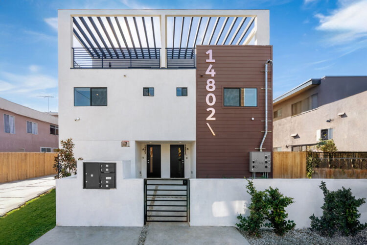 exterior of a three story contemporary townhouse painted white with a brown accent and black trim