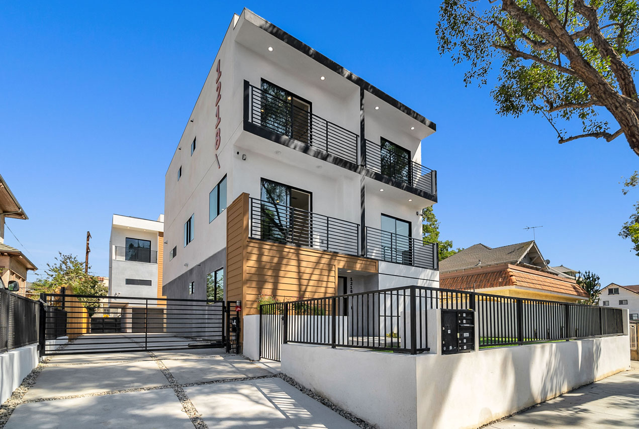 exterior of a three story contemporary apartment building painted white with black trim and wood details