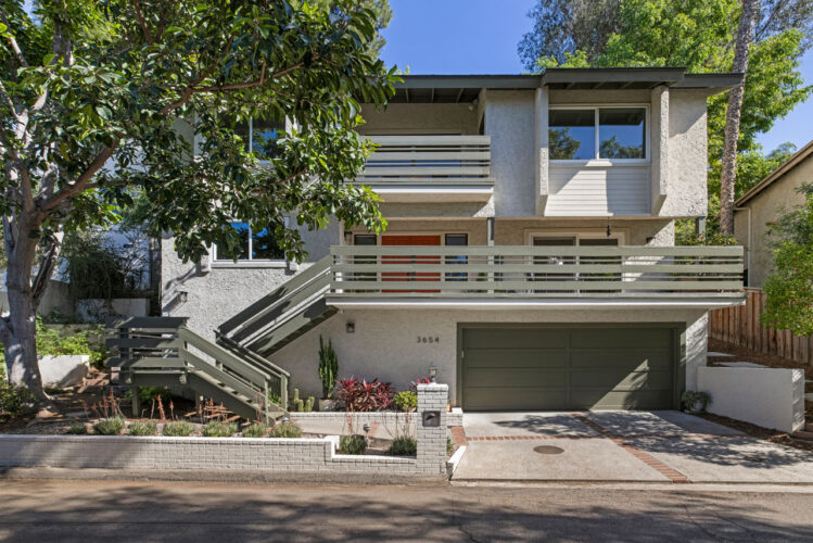 exterior of a three story home with wood railings and green trees