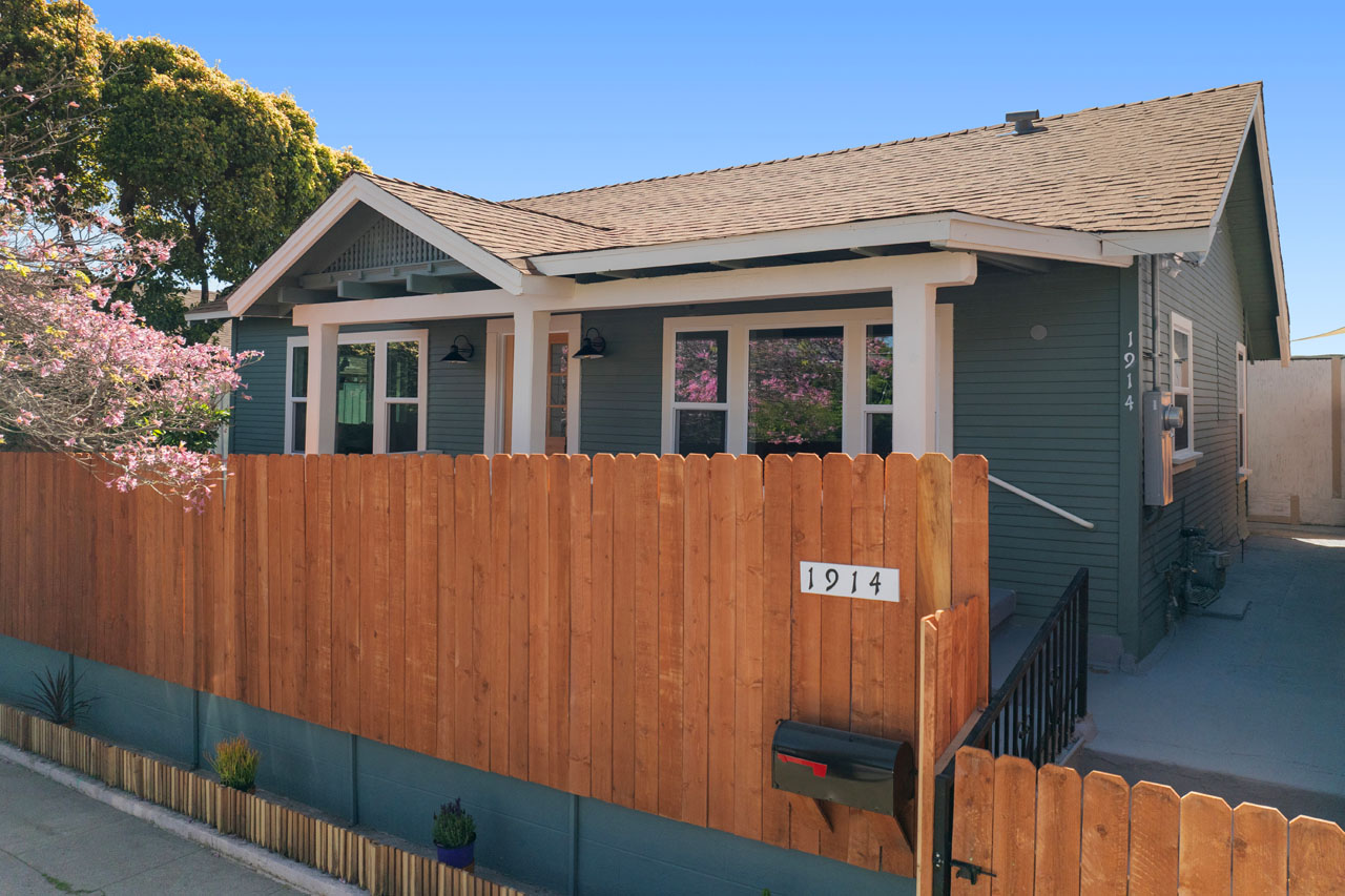 exterior of a bungalow home painted blue with a wood fence