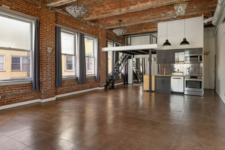 interior of an expansive loft space in a brick building with tiffany lamps and stainless appliances in the kitchen area