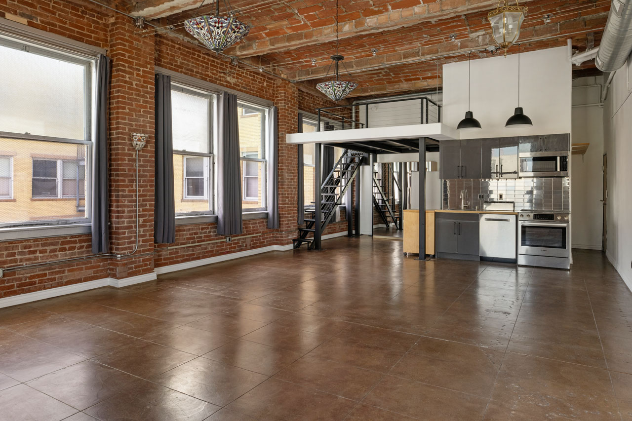 interior of an expansive loft space in a brick building with tiffany lamps and stainless appliances in the kitchen area