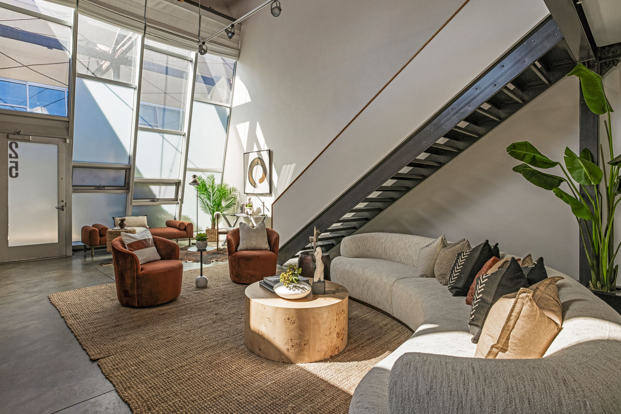 interior of a loft living room space with two story glass windows and a floating staircase