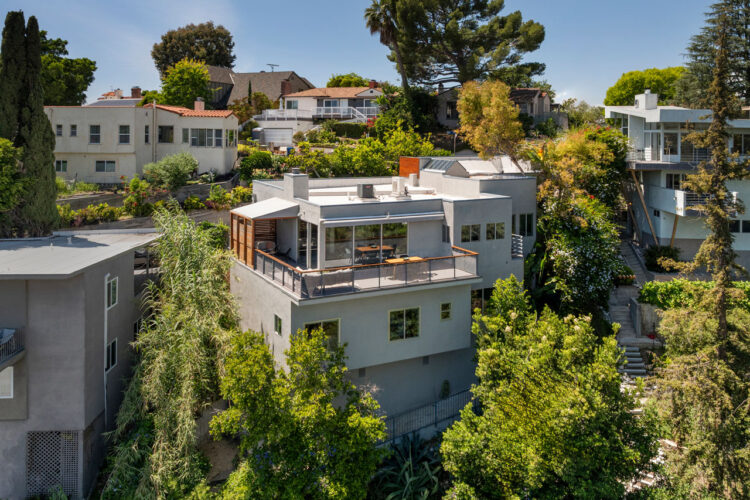 exterior of a contemporary hillside home painted grey surrounded by trees