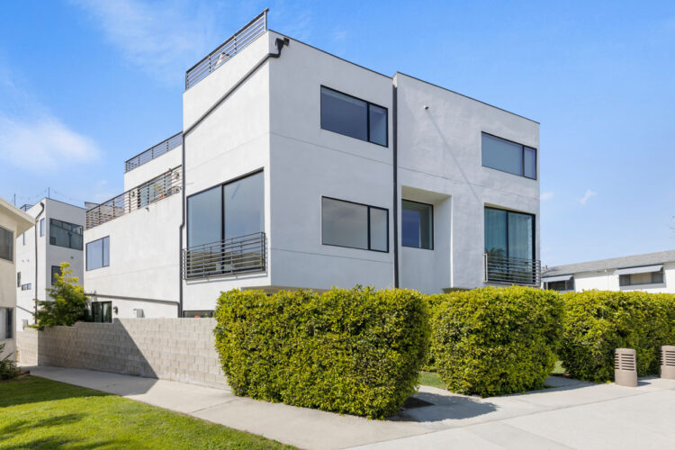 exterior of a contemporary small lot home community, three stories, beige facade, with white garage doors and black trim