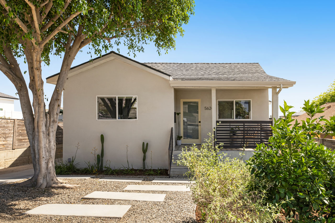 exterior of a 1932 highland park bungalow painted grey with drought tolerant landscaping and a green tree
